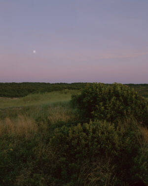 This eight-panel panoramic landscape photograph shows the rising moon on the left and the setting sun on the right from a vantage point overlooking Cape Cod Bay.
