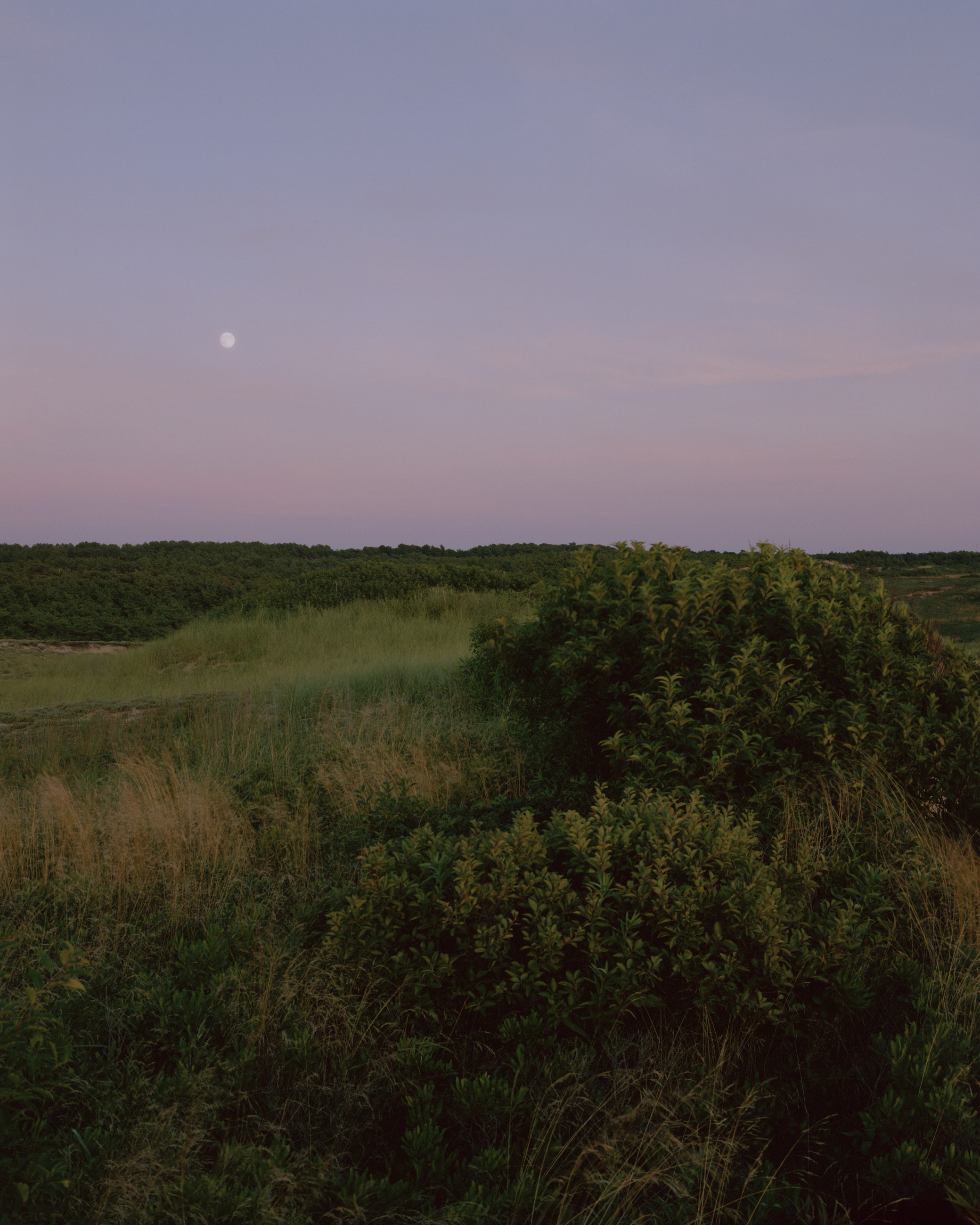 This eight-panel panoramic landscape photograph shows the rising moon on the left and the setting sun on the right from a vantage point overlooking Cape Cod Bay.