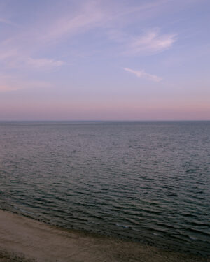 This eight-panel panoramic landscape photograph shows the rising moon on the left and the setting sun on the right from a vantage point overlooking Cape Cod Bay.