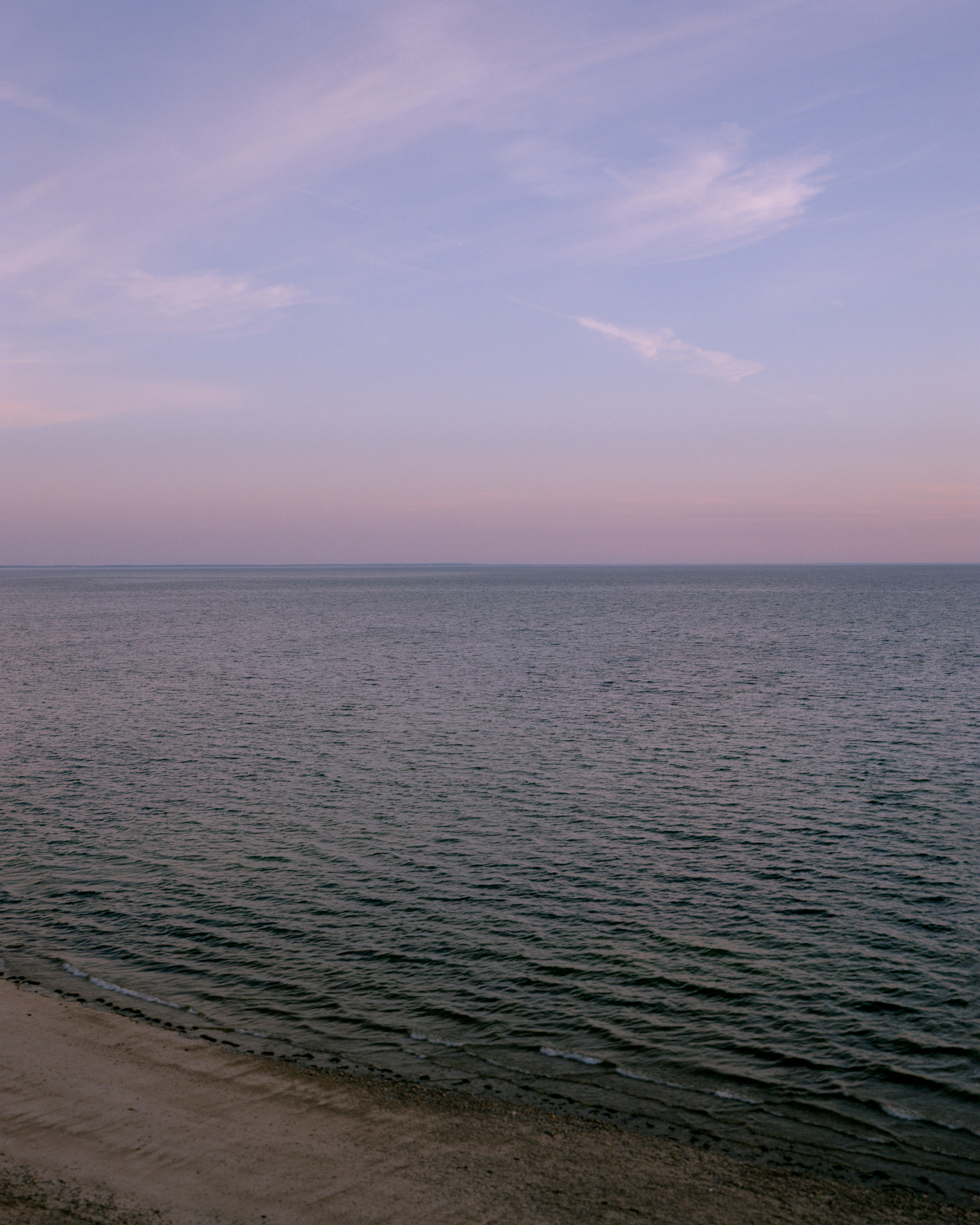 This eight-panel panoramic landscape photograph shows the rising moon on the left and the setting sun on the right from a vantage point overlooking Cape Cod Bay.