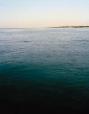 This five-panel panoramic landscape photograph shows flooding Cape Cod Bay tidal water rising up around a field of boulders distributed across a small beach headland.